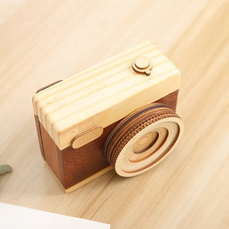 Pine wood camera-shaped music box with rotating mechanism on a wooden base.