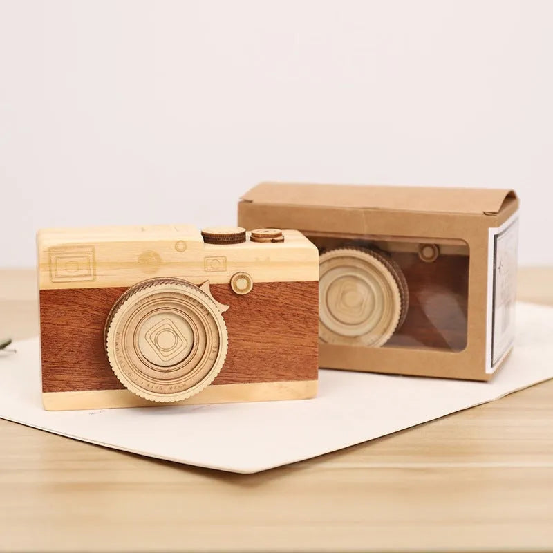 Pine wood camera-shaped music box with rotating mechanism on a wooden base.