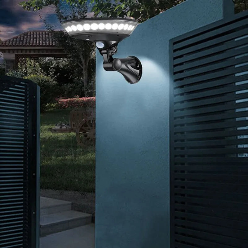 White 360-degree solar-powered outdoor light with motion sensor on a stake for garden installation.