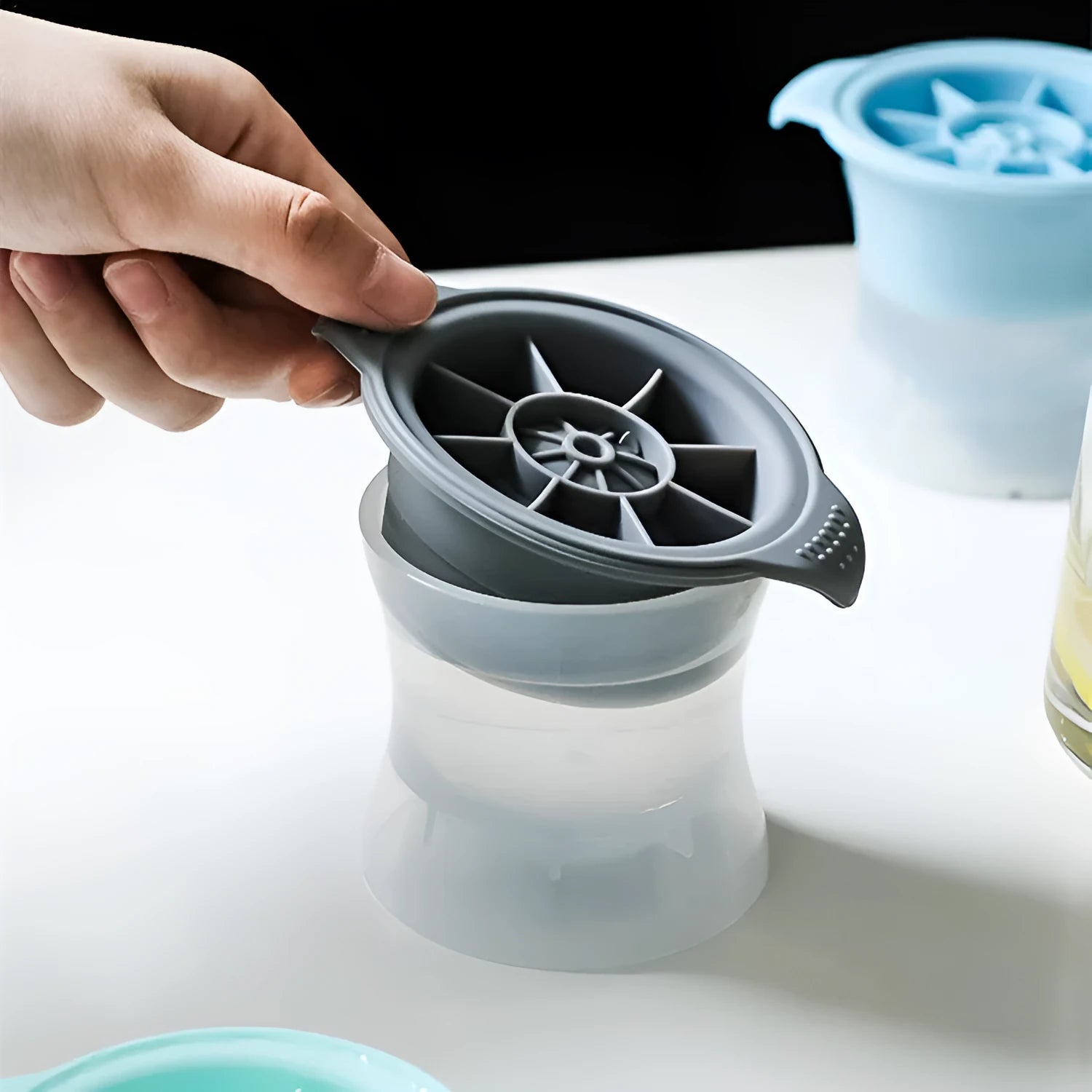 Silicone ice tray showing large mould cavities for ice hockey, spherical, round, and pentagonal shaped ice cubes.