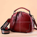 Round leather handbag with zipper opening and soft handle in wine red colour