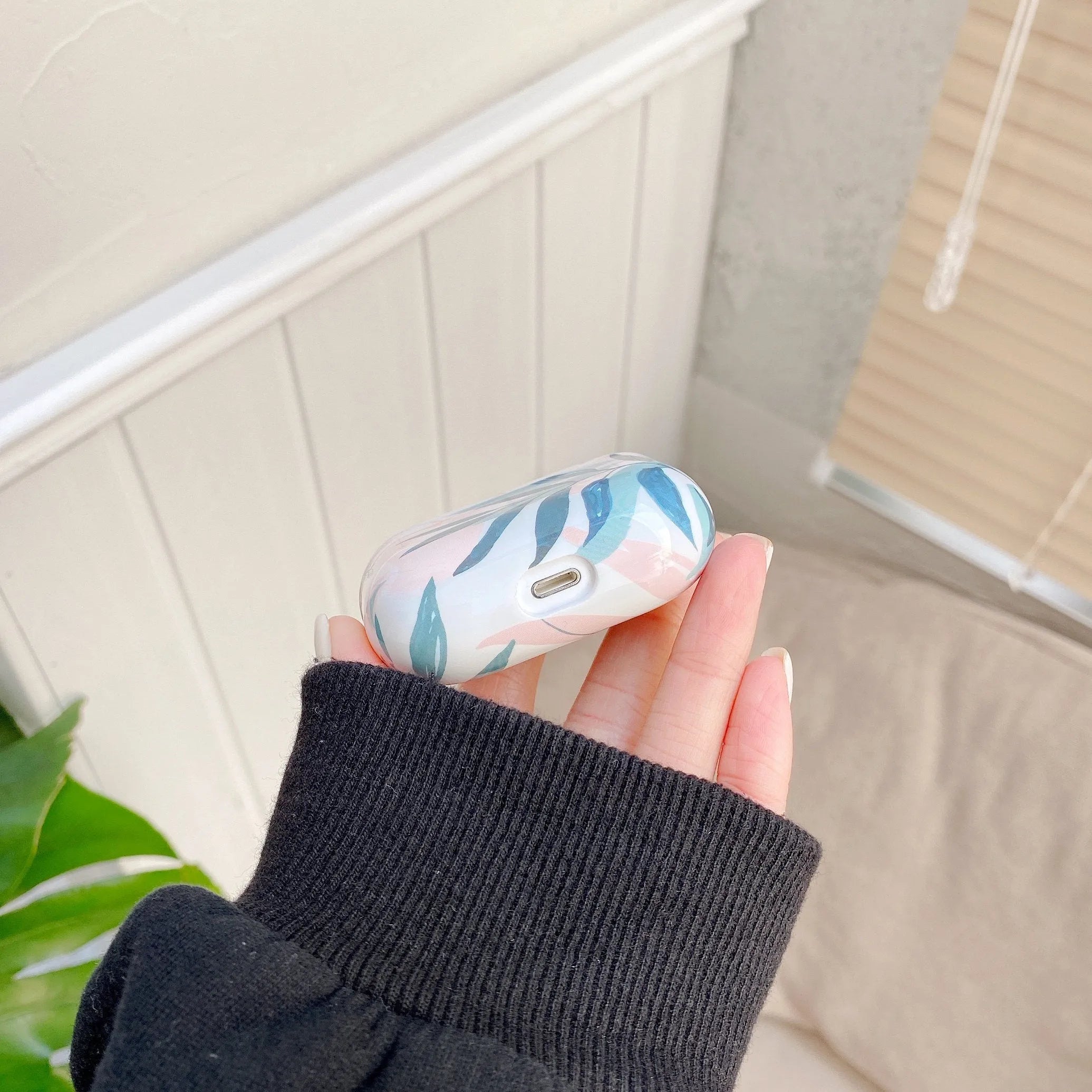 Soft blue TPU AirPods protective case with printed banana leaves tropical design.