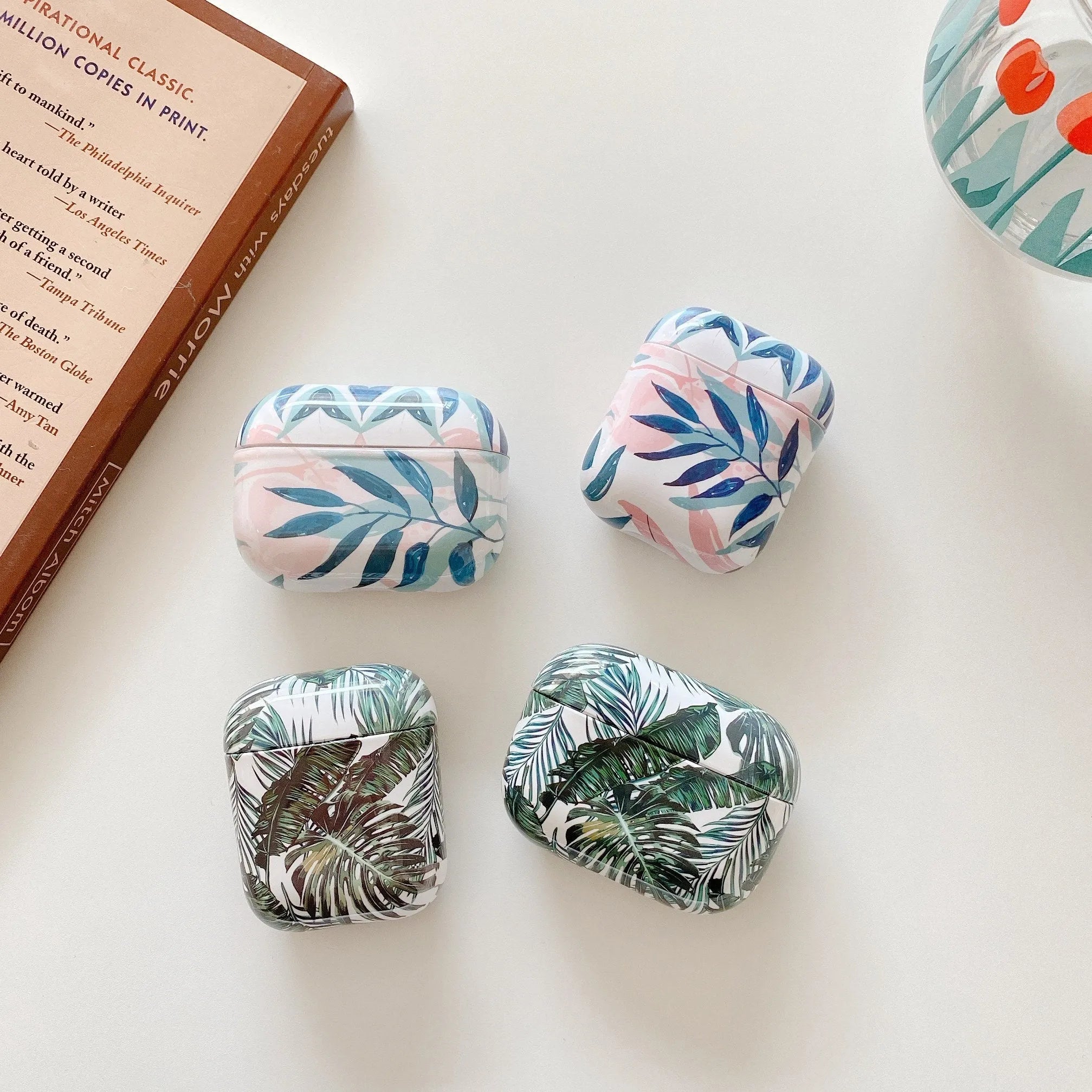 Soft blue TPU AirPods protective case with printed banana leaves tropical design.