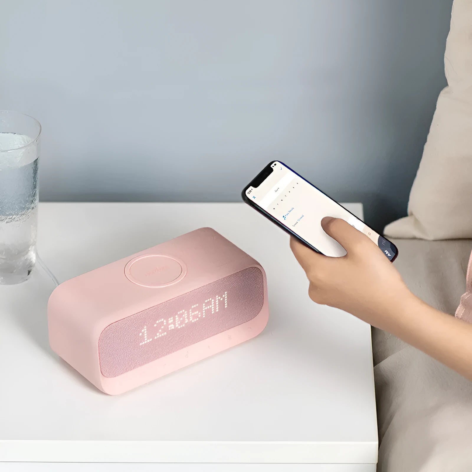 Anker Soundcore white wireless charging Bluetooth speaker and alarm clock on a bedside table.