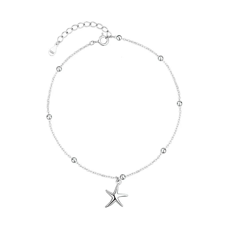 Close-up of a sterling silver anklet with a small starfish charm on a woman's ankle.