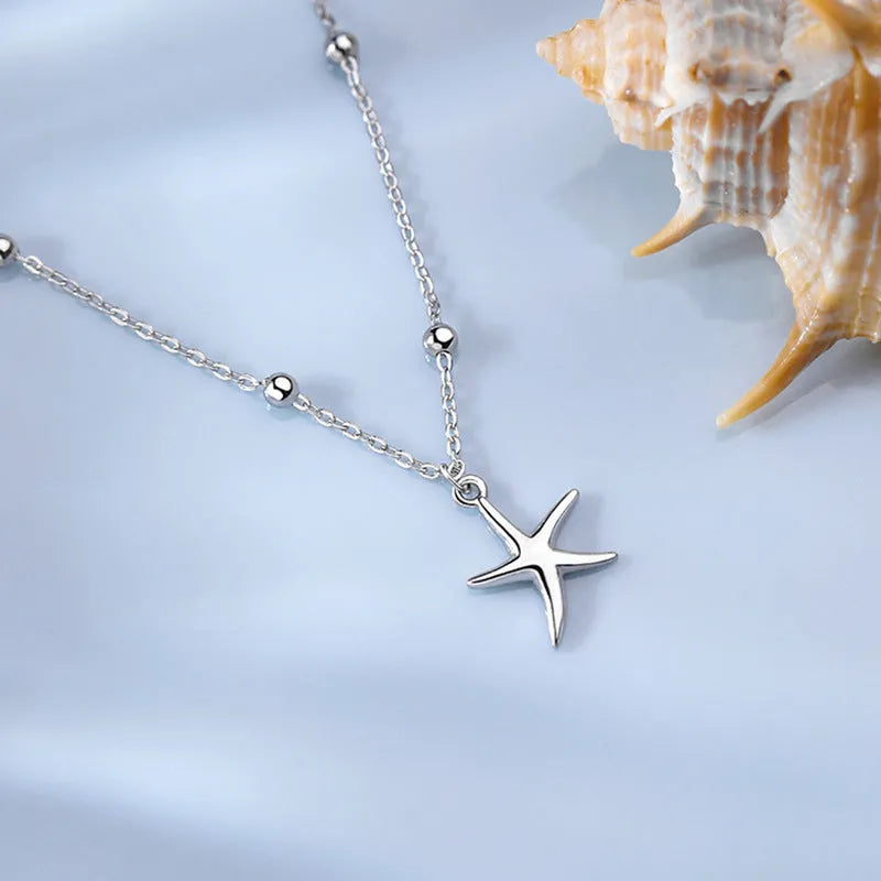 Close-up of a sterling silver anklet with a small starfish charm on a woman's ankle.