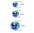 Glow in the dark 3D Earth planet wall sticker in multiple sizes on a dark wall.