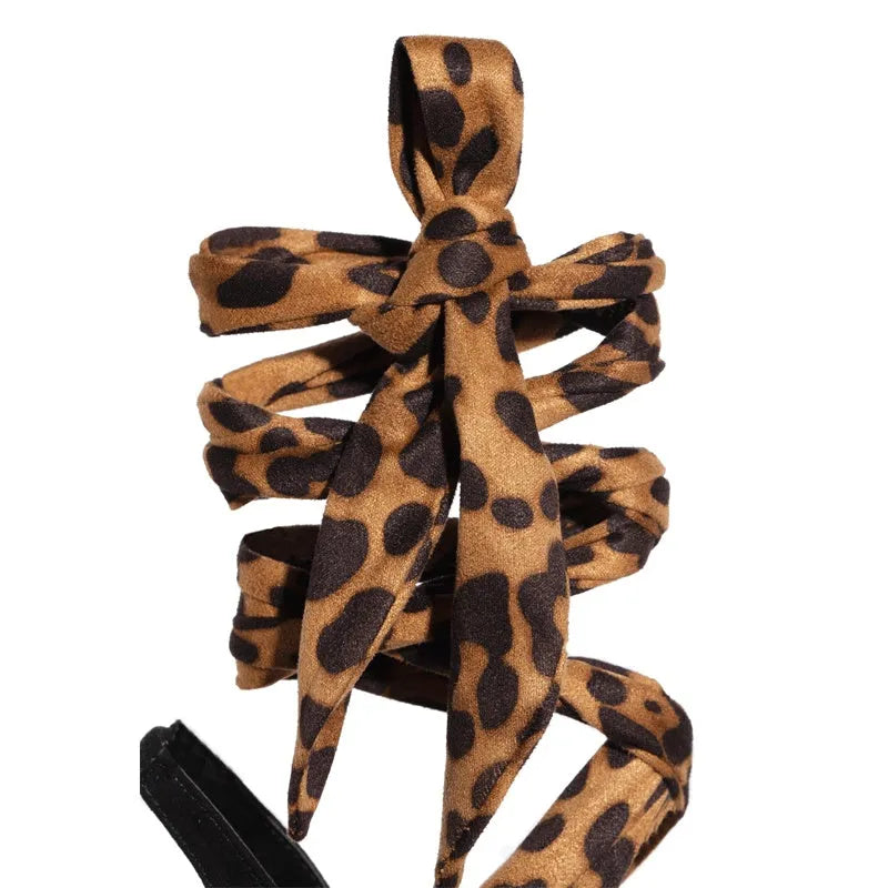 Light brown women's high heels with leopard print pattern and cross strap detail on the foot.