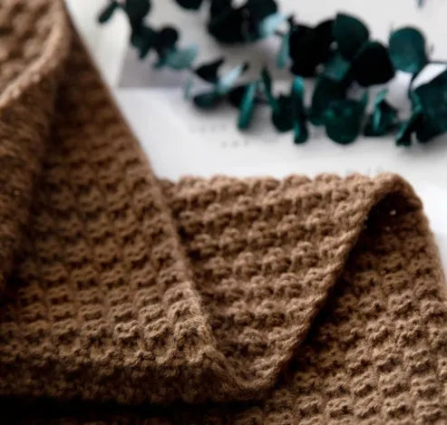 Nordic-style fringed knit acrylic blanket in a plain pattern, shown in a neutral colour on a sofa.
