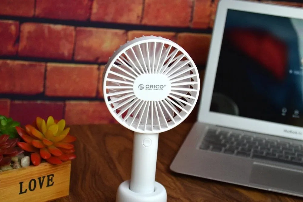 White ORICO FH1 portable USB desktop fan with rechargeable battery on a table.