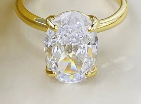 Oval ring with four-claw setting showing hand-cut gemstone in gold and silver colour options