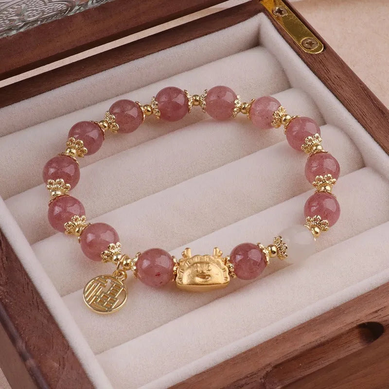 Close-up of a glass and coloured glaze bracelet with animal zodiac modelling and an electroplated floral finish.