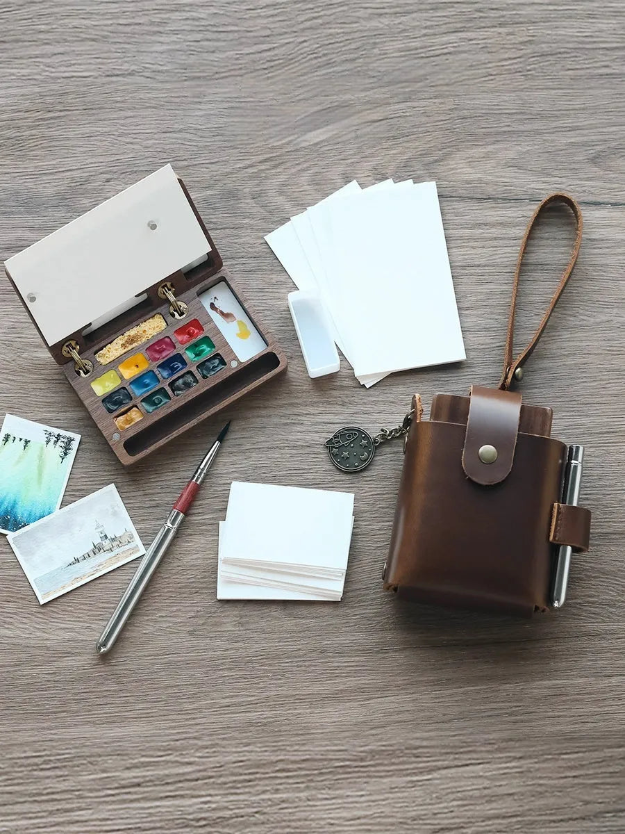 Mini wooden watercolour paint box open showing professional pigment compartments with carrying handle
