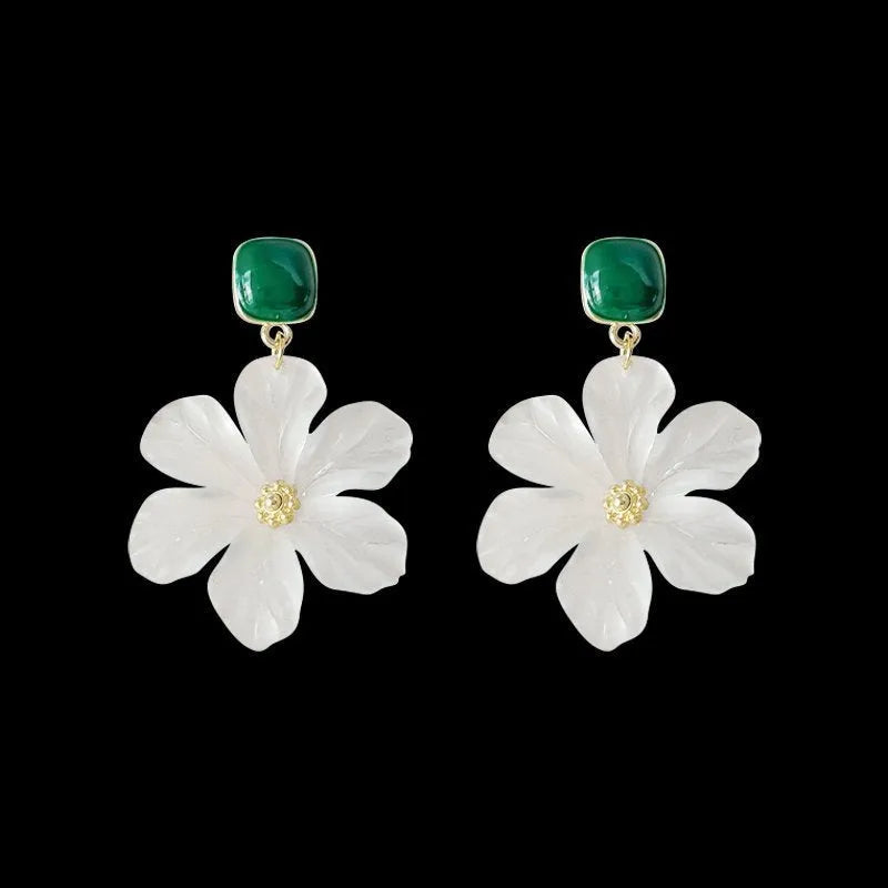 A pair of dark green alloy drop earrings with a floral design and clip-on fittings.
