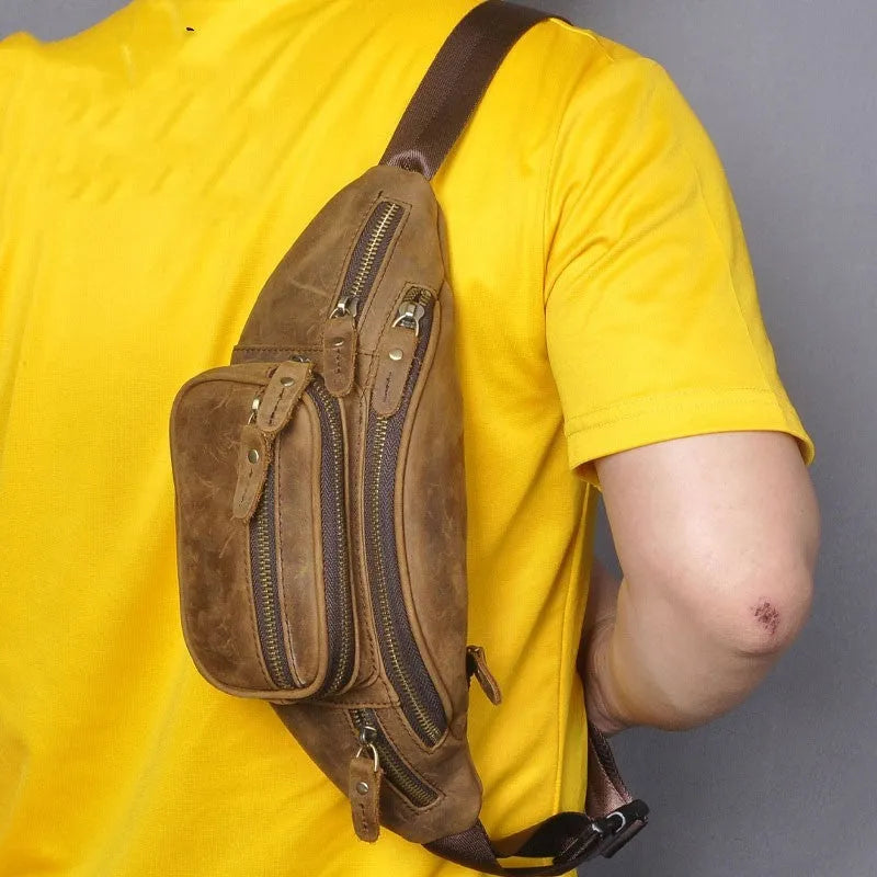 Brown leather messenger bag with a single shoulder strap shown open on a table