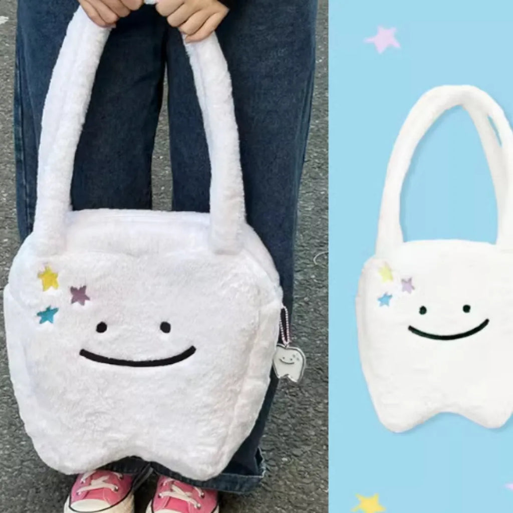 White plush large tooth design shoulder tote bag with zipper closure shown from the front.