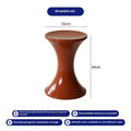Hourglass-shaped plastic shoe changing stool in green colour on a wooden floor.