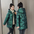 Green loose thick women's winter hooded jacket with long sleeves on a hanger.