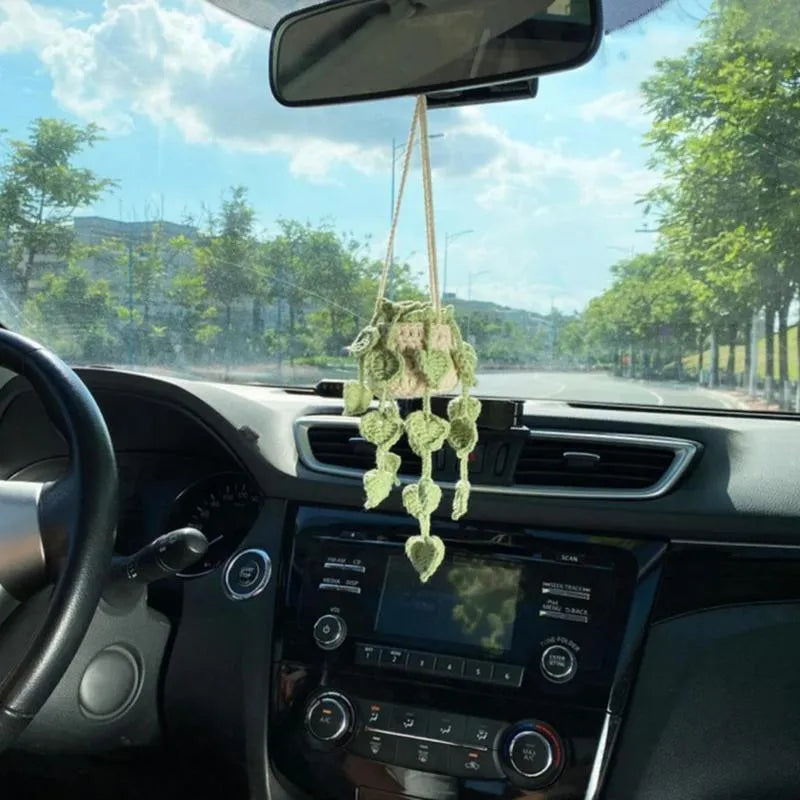 Green and white knitted wool car plant ornament with basin base and hanging rope.