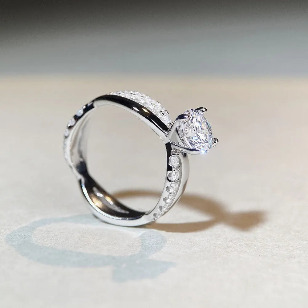 A geometric twisted silver ring with a 1 karat moissanite stone in a four-claw setting.