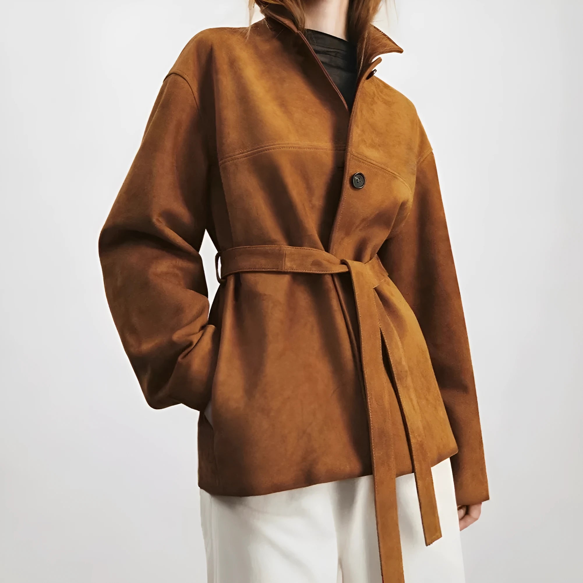 Women's belted caramel cashmere coat with leather stitching and a Peter Pan collar.