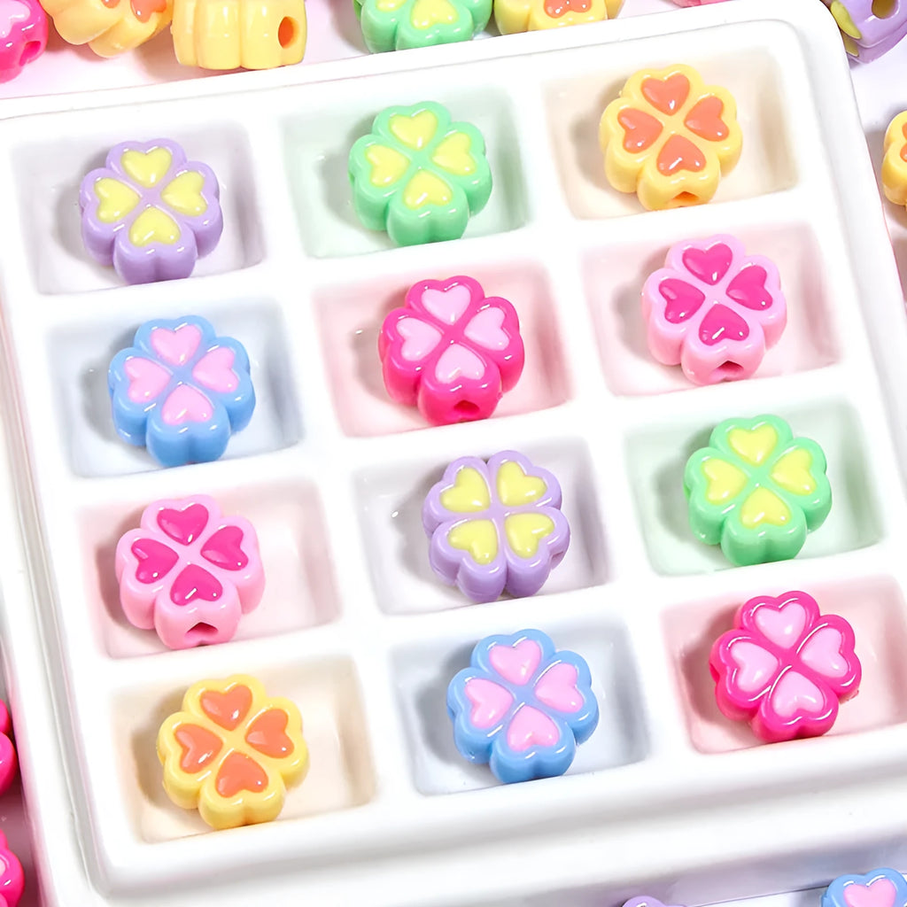 Frosted acrylic four-leaf clover shaped beads in mixed colours on white background