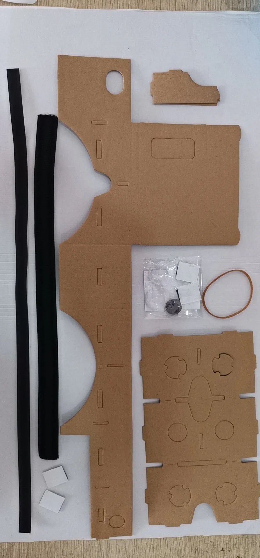 Foldable pink and white cardboard VR glasses headset with lenses and rubber head strap for smartphones.