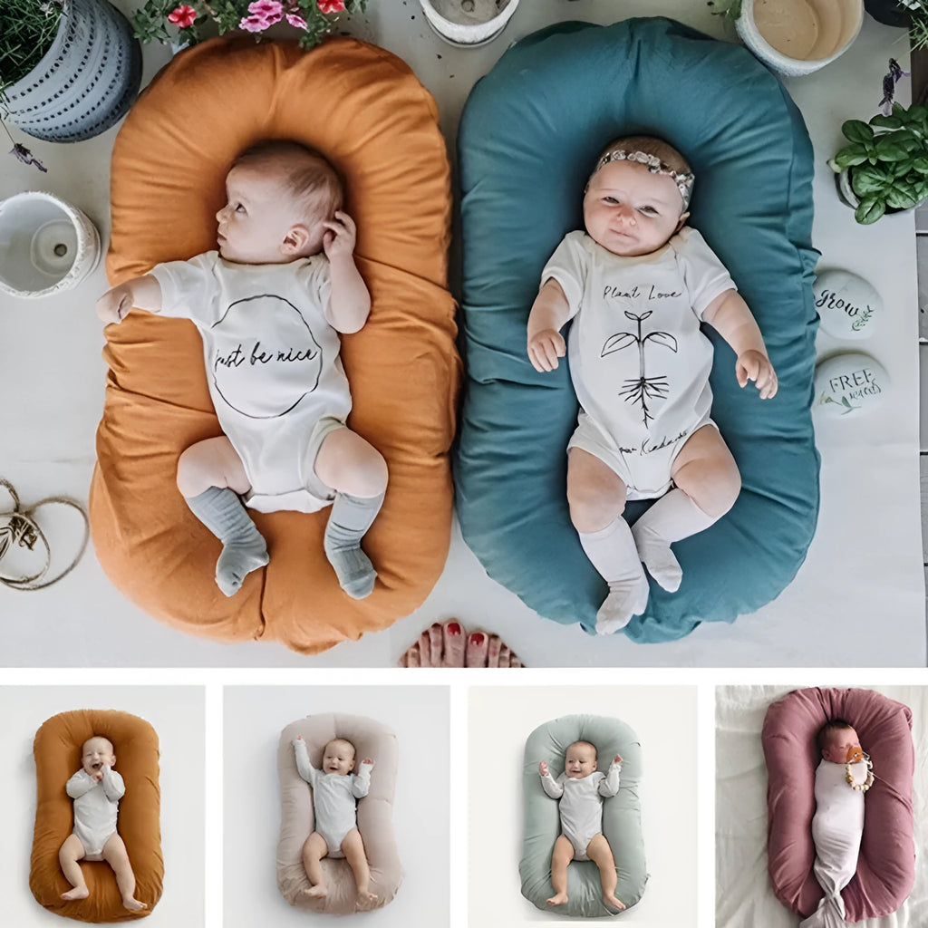 Beige portable cotton baby nest crib for newborns on a neutral background