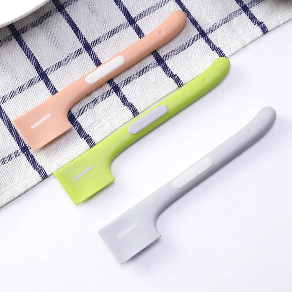 Green long-handled pet feeding spoon for scraping wet food from cans.
