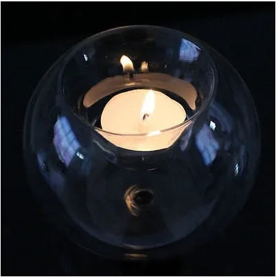 Handmade round hollow glass candle table centrepiece on a wooden surface.