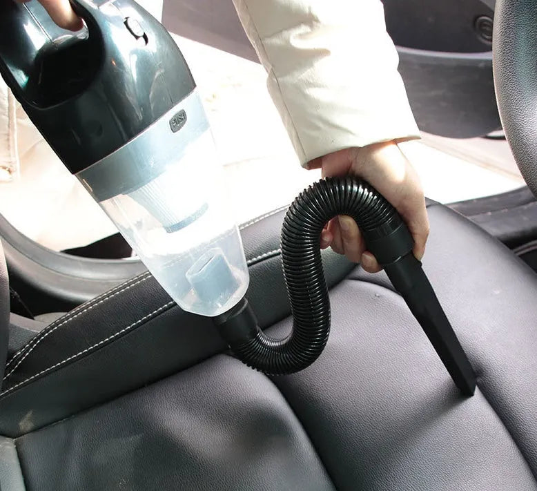 Orange, blue, and black coloured portable 12V handheld car vacuum cleaner with nozzle attachments on a car seat.