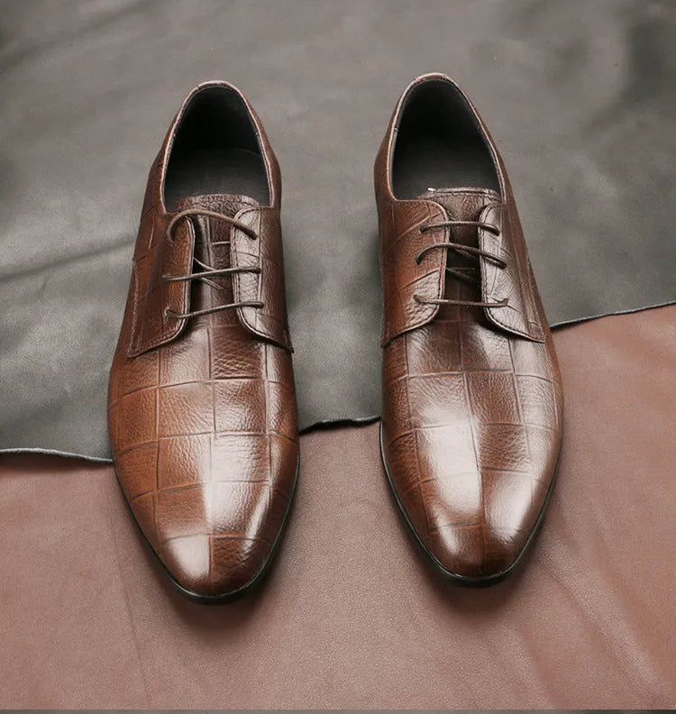 Men's black cow leather derby shoes with a pointed toe and rubber sole on a grey background.