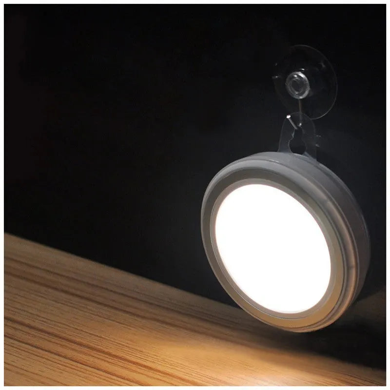 Circular white motion sensor LED light with five LEDs, shown mounted inside a dark wardrobe.