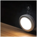 Circular white motion sensor LED light with five LEDs, shown mounted inside a dark wardrobe.