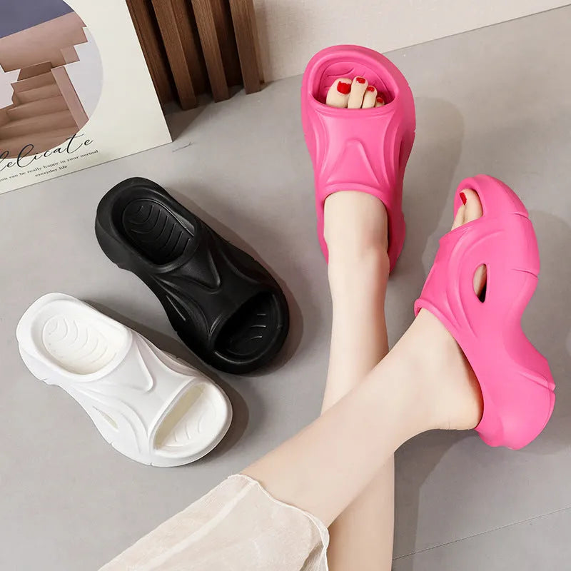 Women's white thick-soled EVA beach slippers with round toe on sand.