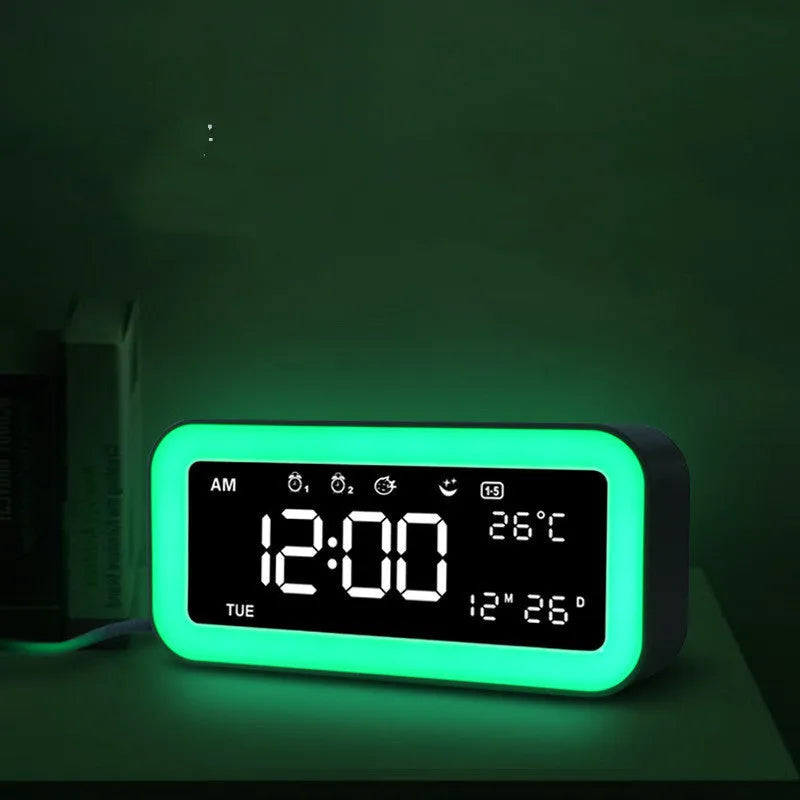 Blue rectangular LED digital alarm clock with multicoloured lighting and Bluetooth speaker on a bedside table.