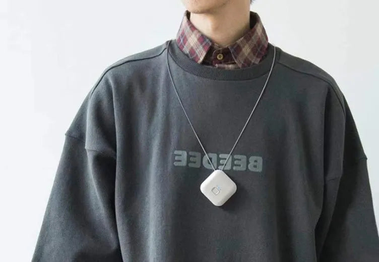Small pink wearable USB air purifier necklace on a person, showing compact size.