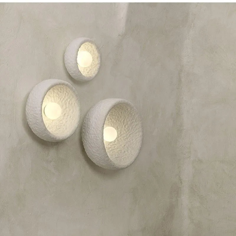 Japanese minimalist wall lamp with a round resin shade, shown in a modern room setting.