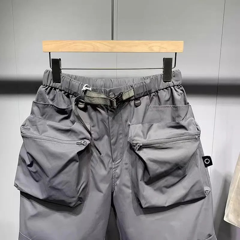 Men's loose-fit black work shorts with pockets, shown on a model, above the knee length.