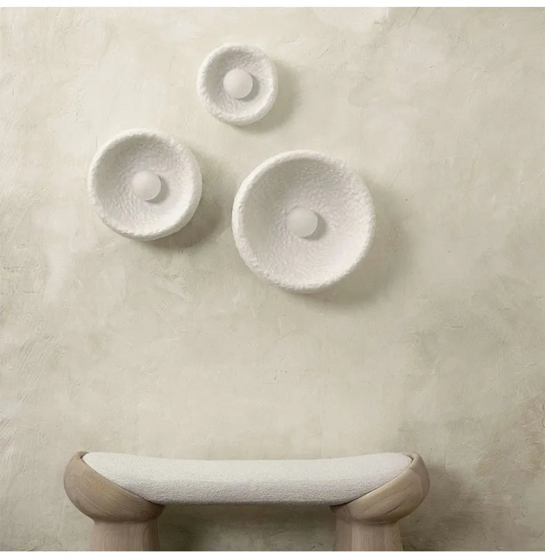 Japanese minimalist wall lamp with a round resin shade, shown in a modern room setting.