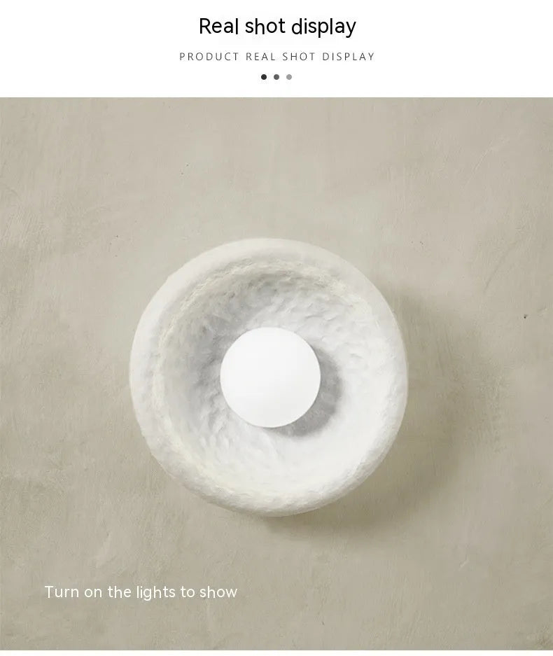 Japanese minimalist wall lamp with a round resin shade, shown in a modern room setting.