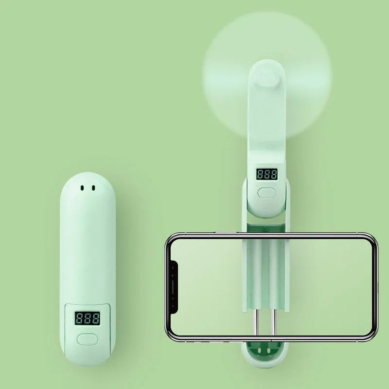 Green folding portable USB rechargeable mini fan with plastic blades on a white background.