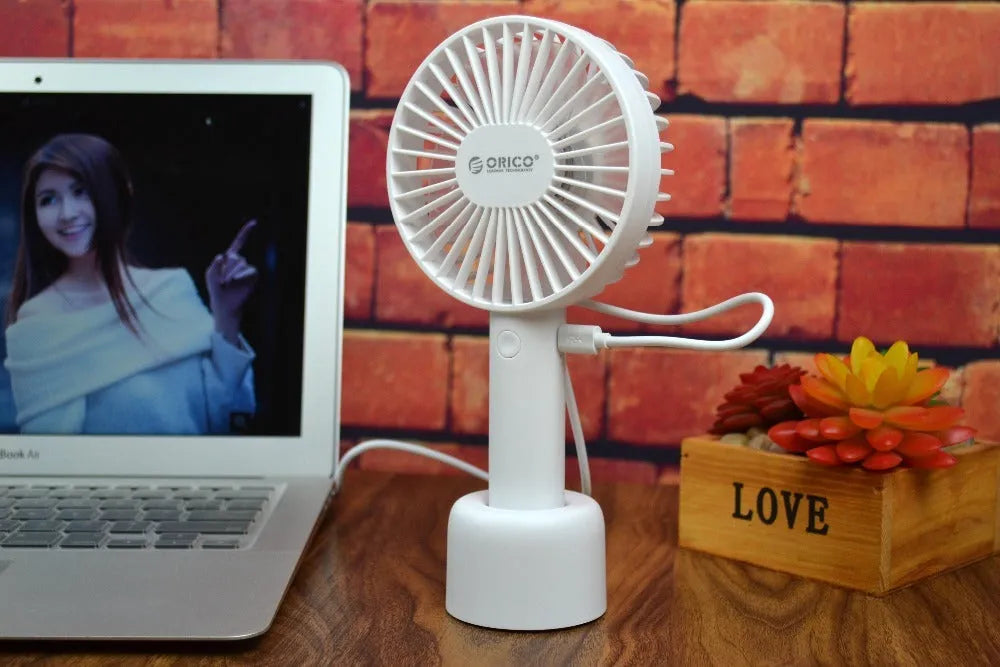 White ORICO FH1 portable USB desktop fan with rechargeable battery on a table.