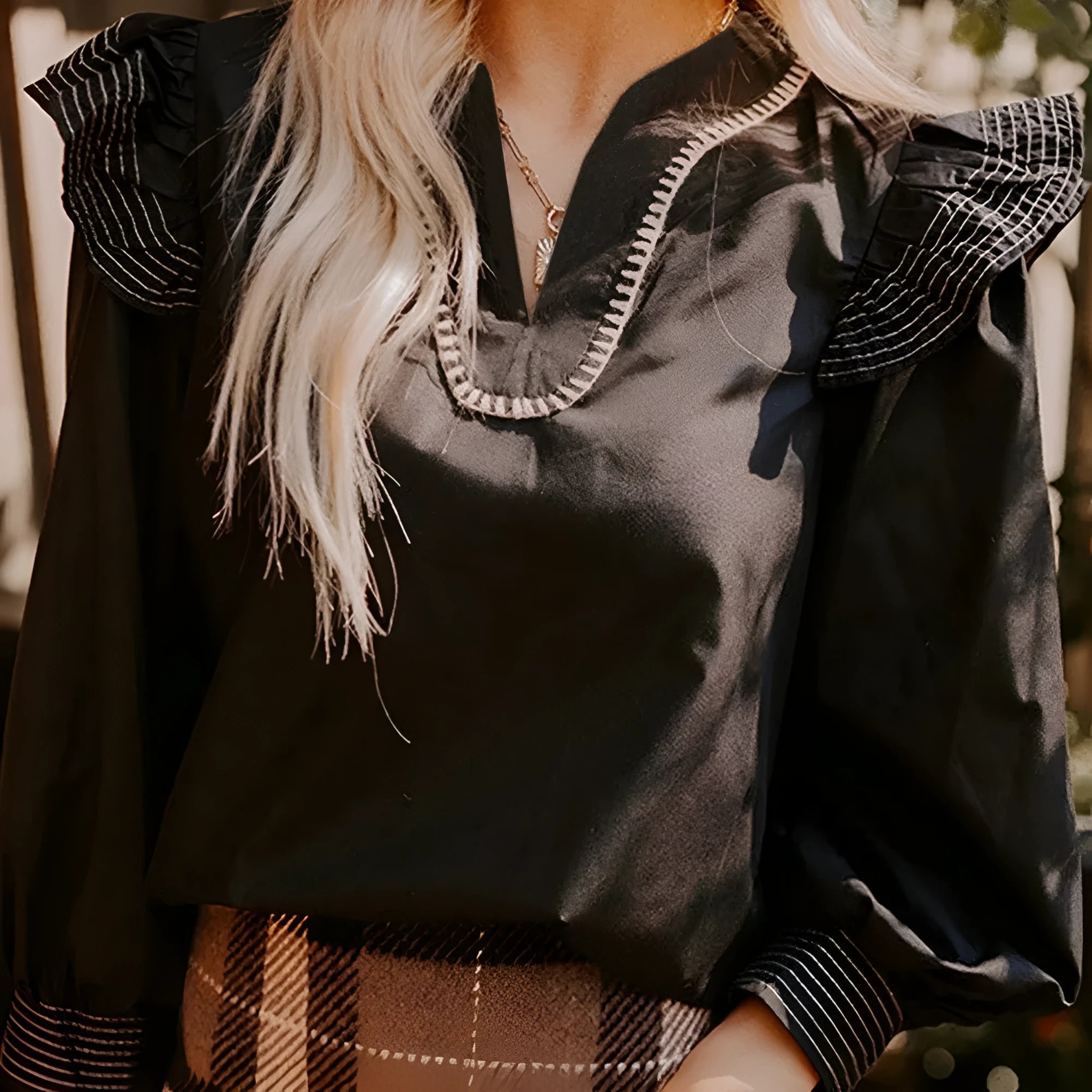 Black long sleeve V-neck blouse with contrast stitching and three-quarter ruffle sleeves.