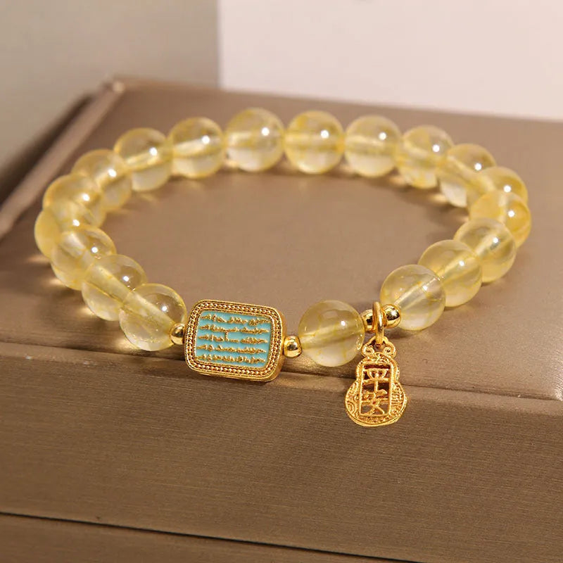 Women's yellow citrine crystal bracelet with sparkling rhinestone details on a white background.