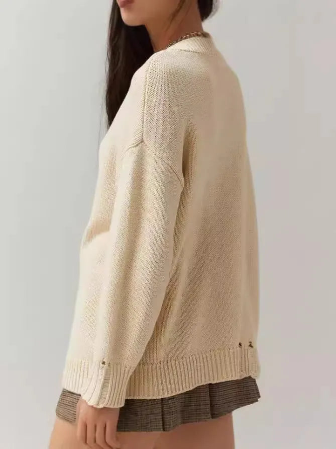 Women's milky white acrylic jacquard pullover sweater with round neck and long sleeves laid flat.
