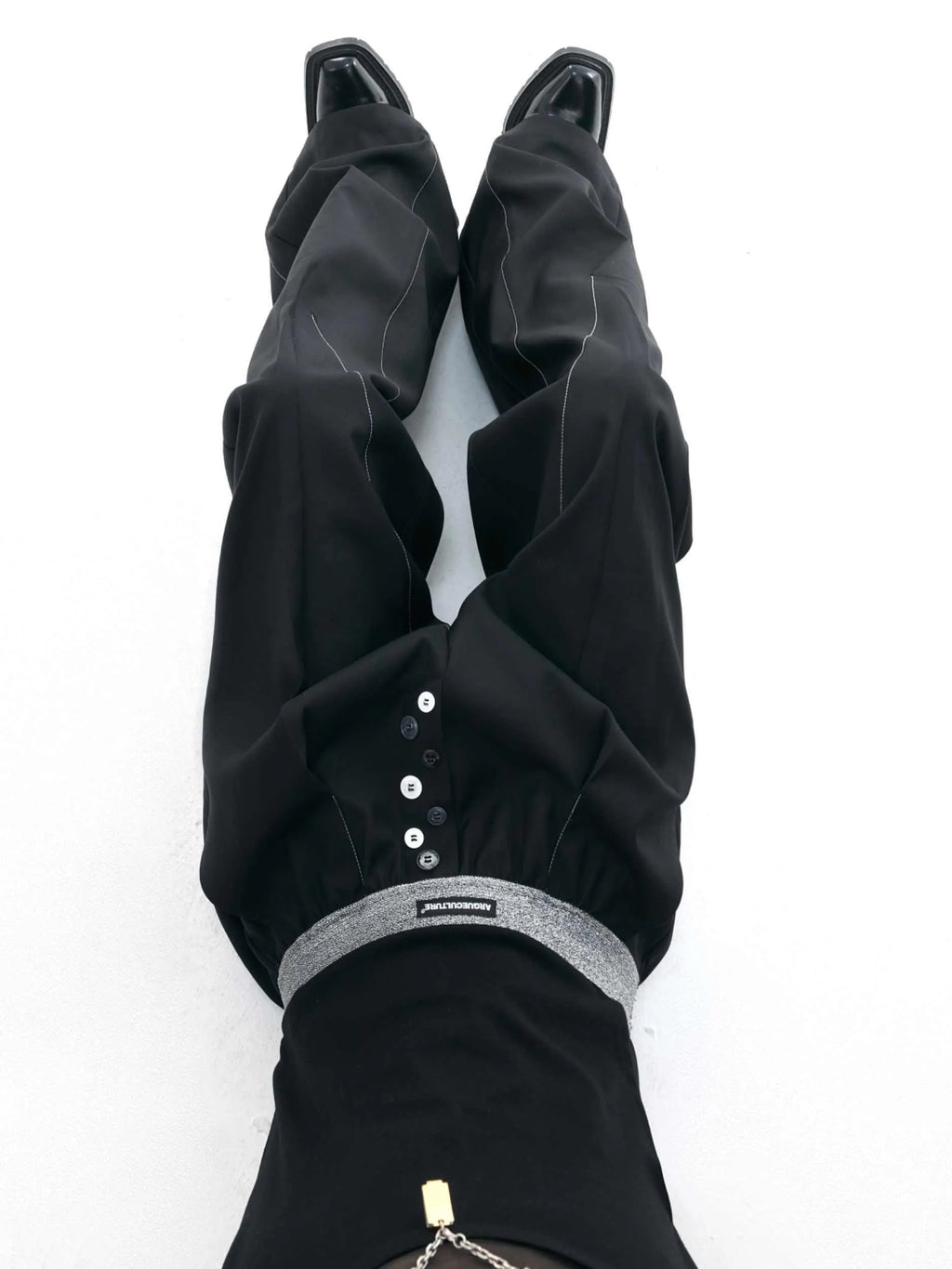 Drooping straight suit pants in black and grey colours showing high waist and button open line design detail.
