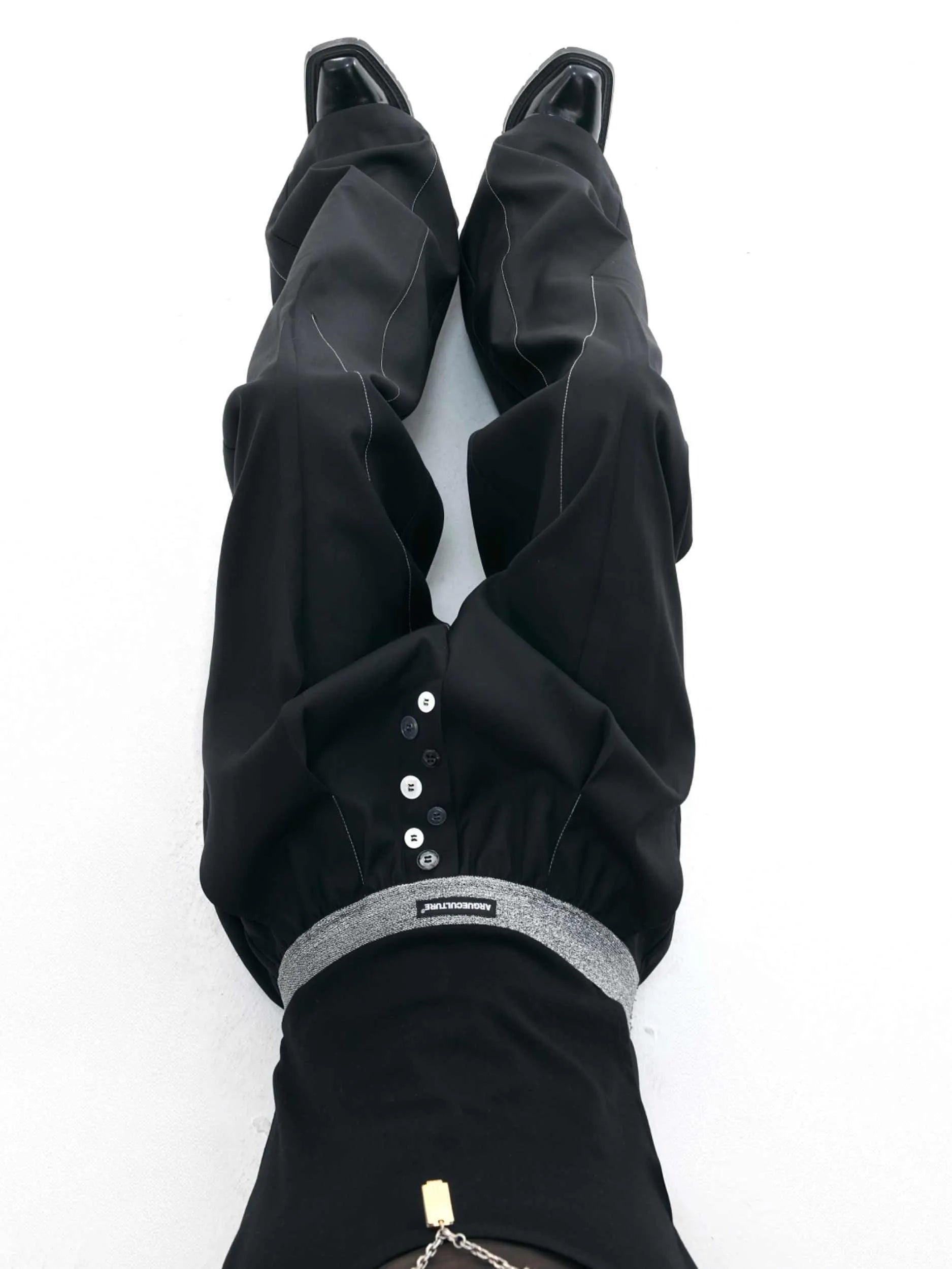 Drooping straight suit pants in black and grey colours showing high waist and button open line design detail.