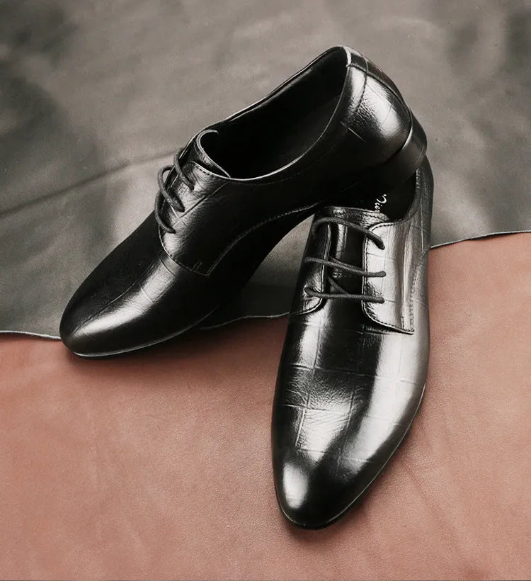 Men's black cow leather derby shoes with a pointed toe and rubber sole on a grey background.