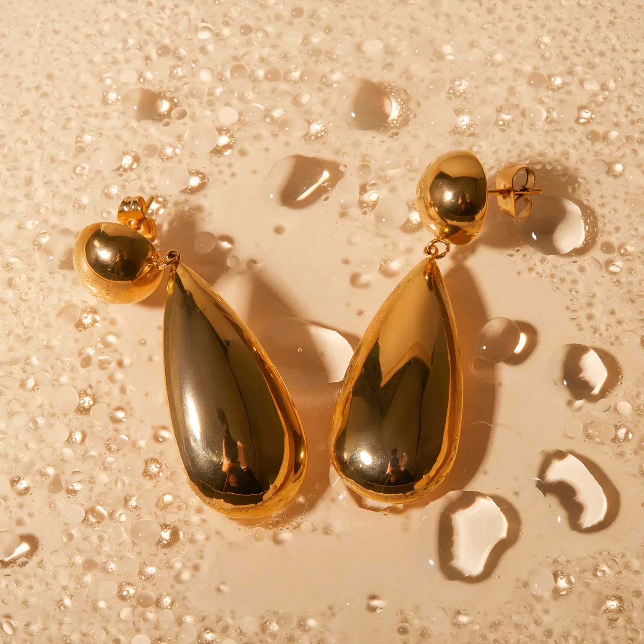 Gold electroplated stainless steel earrings with geometric water droplet hemisphere pendant design